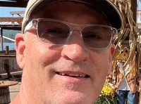 A couple is smiling in front of the Showboat Branson Belle sign at Table Rock Lake, surrounded by autumn decorations.