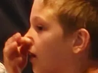 The image shows an audience seated in a theater with a bright and ornate stage set up for a performance.