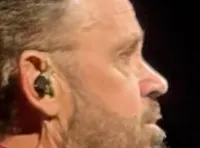 Three people are standing on stage under a sign that says 