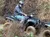 A person wearing a helmet and mask is riding an ATV through a grassy and wooded area.