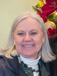 A couple is posing in front of festive Christmas trees and a 