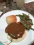 A plate of food featuring a roll, mashed potatoes with gravy, and green beans sits on a countertop.
