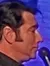 A man and a woman are singing to each other on a stage with a colorful background.