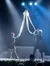 Two performers on stage are holding aerial silks under dramatic lighting.