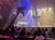 The image shows a theatrical pirate-themed performance on stage, viewed from an audience seated at tables, with dramatic lighting and ship masts as part of the set design.