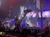 The image depicts a lively pirate-themed stage performance with a detailed ship set and an audience enjoying the show.