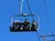 Three people are sitting on a ski lift against a clear blue sky, with one person waving.