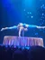 Two acrobats perform an impressive balancing act on a stage under blue lighting.