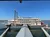 A large, vintage paddlewheel riverboat is docked at a pier against a clear blue sky.