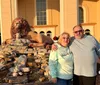 Three people are standing in front of a building with large arches, next to a lion sculpture on a rock display.
