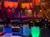 The image shows a dining setup in front of an indoor stage designed like a ship's deck, illuminated with colorful lights and surrounded by a nautical theme.