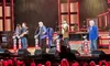 A group of musicians is performing on stage under colorful lights with 