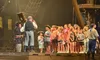 A group of children are standing on a stage with actors dressed as pirates during a theatrical performance.