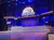 Musicians are performing on a stage with a display featuring the 