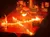 A performer is on stage surrounded by a pattern of fire during a dramatic nighttime show.