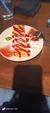 A dessert with red sauce drizzled on a rectangular piece, garnished with a strawberry and whipped cream on a white plate.