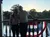 A silhouetted couple stands on a balcony at sunset with a decorative flag behind them.