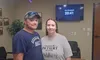 A couple poses in an escape room with a screen showing they escaped in 20:41.