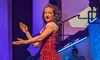 A performer in a red plaid costume is dancing on a stage with vibrant lighting and decorative elements.