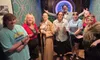 A group of people in various costumes pose together in a themed room with a 