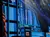 The image shows a stage with blue lighting and a sign reading 