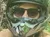 A person wearing a helmet and sunglasses is riding a blue all-terrain vehicle on a dirt path through a forest.