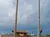 Two people are climbing tall wooden poles in a lumberjack-themed outdoor setting.