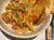 A bowl of penne pasta topped with diced tomatoes, green onions, and grated cheese is served alongside two pieces of toasted garlic bread.