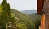 A railing-lined staircase descends alongside a wooden building, offering a view of a lush, green mountainous landscape under a clear sky.