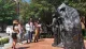 A group of people interacts with and observes a large sculptural installation on a sunny day.
