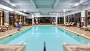 The image shows an indoor swimming pool area with lounge chairs and facilities, typically found in a hotel or recreational center.
