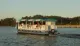 A ferry named Jamestown Discovery is cruising on the water with passengers on board during what appears to be late afternoon.
