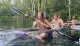 A group of individuals is kayaking in clear water, with one person in a transparent kayak revealing the underwater view.
