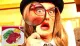 The image shows a person with exaggerated facial expressions, wearing a hat and glasses, holding a large magnifying glass up to one eye.