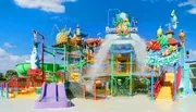 This is a colorful and vibrant water play structure for children with slides, sprayers, and a large tipping bucket, under a clear blue sky.
