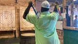 A person is poised to throw an axe at a wooden target in an indoor axe throwing facility.