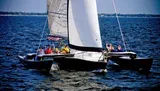 A group of people are enjoying a day of sailing on a multi-hull sailboat on a large body of water.