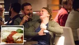 Two people are sharing a jovial moment with laughter at a social gathering.