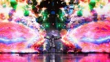 A person in a metallic suit stands with arms outstretched against a vibrant, psychedelic backdrop of colorful, abstract lights.