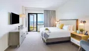 This is a neatly arranged hotel room with a balcony overlooking the sea.