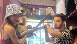 Two people are playfully posing with oversized props as swords inside a room filled with various colorful decorations and novelty items.