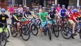 A group of smiling young people in helmets are poised on mountain bikes, seemingly ready for a group ride.