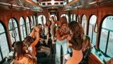 A group of people are joyfully dancing and celebrating inside a moving trolley.