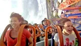 This is an action-packed photo of people of various ages experiencing the thrill of a roller coaster ride, displaying a range of emotions from exhilaration to joy.