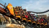 Thrill-seekers experience a sharp turn on a roller coaster with expressions of excitement and enjoyment.