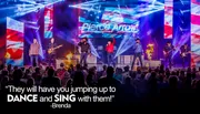 A band performs energetically on stage with vibrant lighting, surrounded by flames and a cheering audience, accompanied by a quote praising their ability to make people 