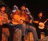 A trio of musicians in cowboy hats perform with acoustic instruments on stage and a small inset shows a child enjoying a meal
