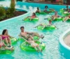 Three people are enjoying a sunny day at a water park sliding down in a large inflatable ring with big smiles on their faces