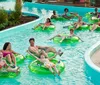 Three people are enjoying a sunny day at a water park sliding down in a large inflatable ring with big smiles on their faces