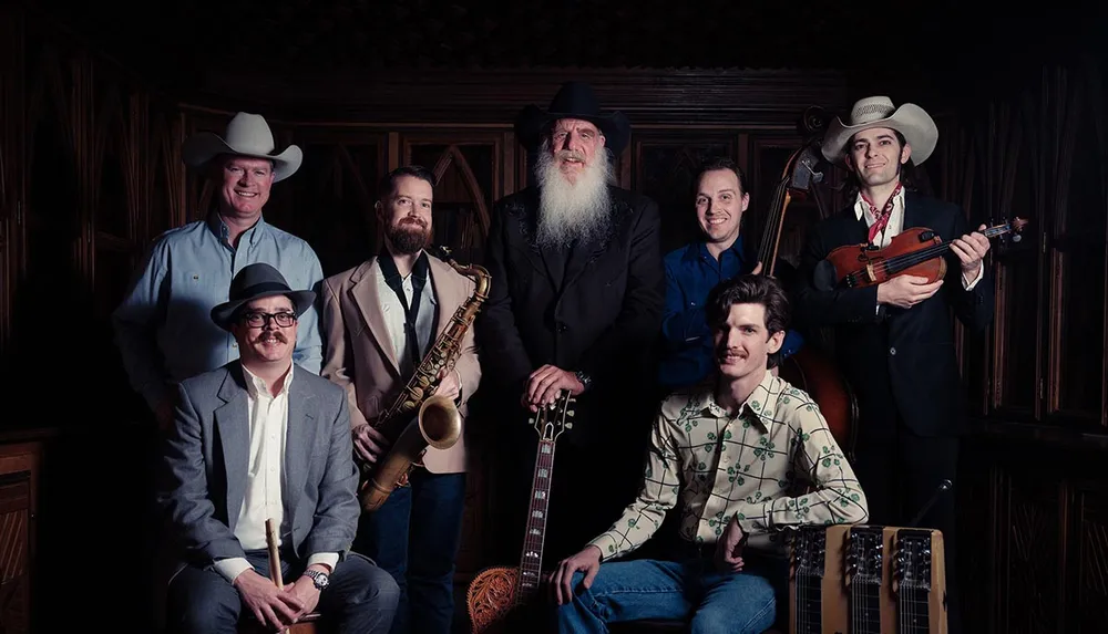 A group of seven men dressed in cowboy and formal attire pose with musical instruments including a saxophone violin and guitar